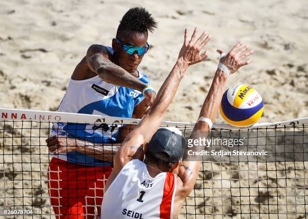 Diaz Nivaldo of Cuba spikes the ball against Robin Seidl of Austria during the Men's Main draw elimination match between Cuba and Austria on August...
