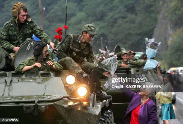 Two women give flowers to Russian soldiers as they leave South Ossetia at the North-South Ossetia border, some 60 km outside Vladikavkaz on August...