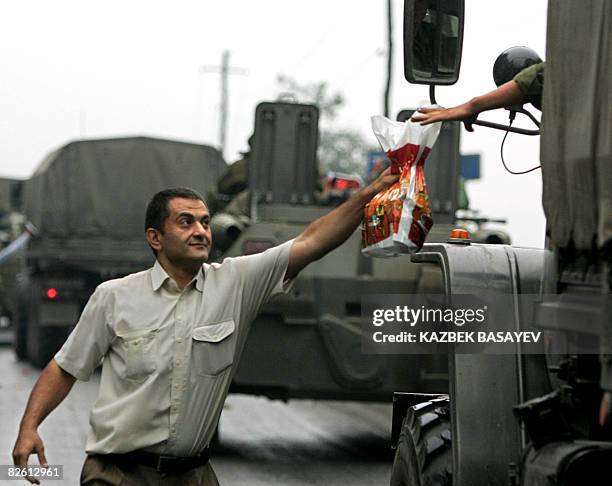 Man gives a plastic bag to a driver as Russian soldiers leave South Ossetia at the North-South Ossetia border some 60 km outside Vladikavkaz on...