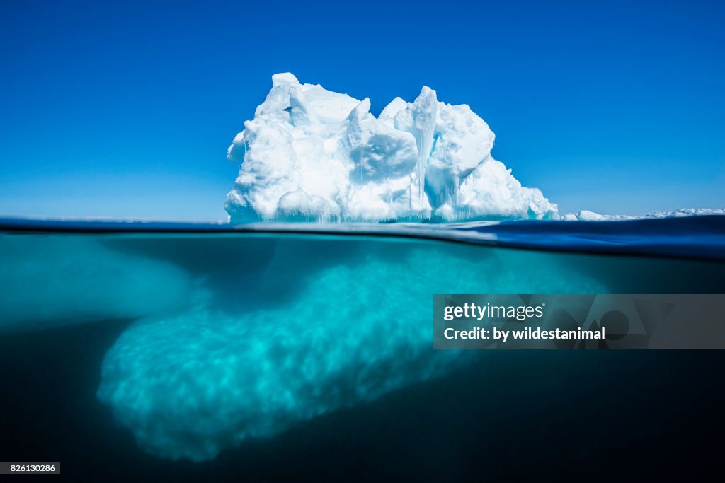 Split view of an iceberg at the ice floe edge showing what is above and below the waterline on a bright sunny summer's day in Admiralty Sound, Baffin Island, Canada.