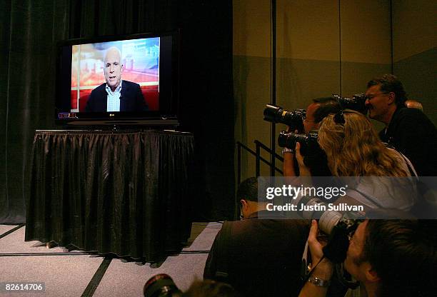 Photographers cover U.S. Sen. John McCain broadcasted on a monitor making a statement during a press conference at the at the River Center August 31,...