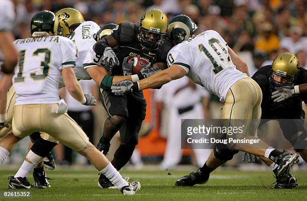 Running back Darrell Scott of the University of Colorado Buffaloes rushes as Jeff Horinek and Wade Landers of the Colorado State University Rams make...