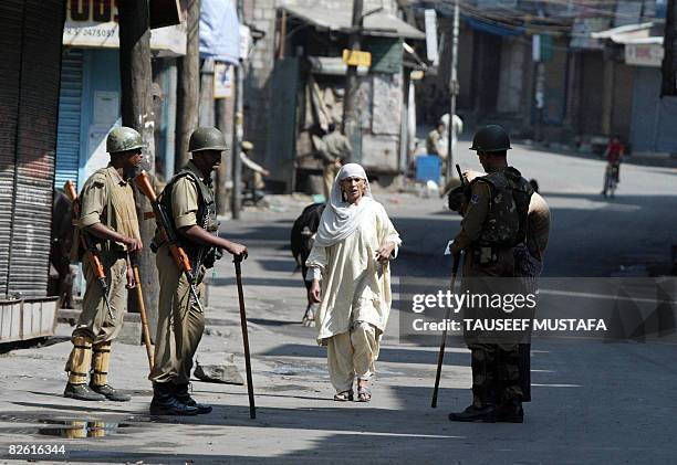 An Indian Kashmiri woman is stopped by patrolling Indian Central Reserve Police Force soldiers as she walks on a deserted street in Srinagar on...