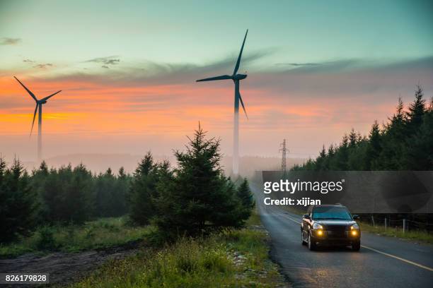 wind turbine with road - green colour car stock pictures, royalty-free photos & images