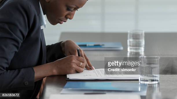 businesswoman signing document - blue blazer stock pictures, royalty-free photos & images