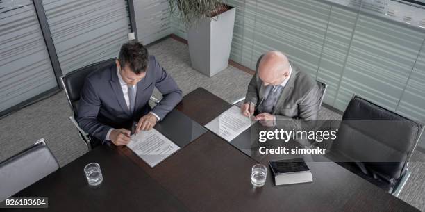 two businessmen signing contract - conference table stock pictures, royalty-free photos & images