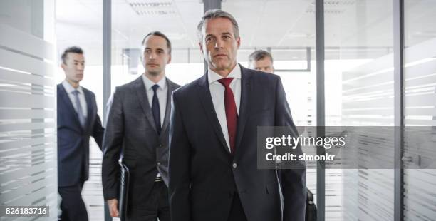 businessmen walking down hall and into office for meeting - navy blue stock pictures, royalty-free photos & images