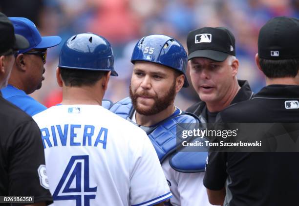 Russell Martin of the Toronto Blue Jays is restrained by bench coach DeMarlo Hale and third base coach Luis Rivera after being ejected by home plate...