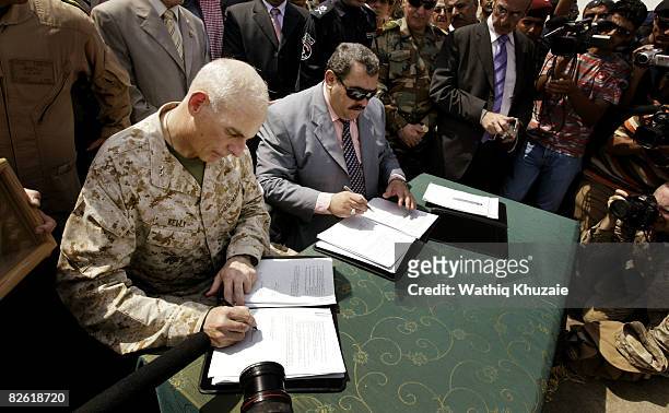 Marine Maj. Gen. John Kelly and Anbar Province Governor Maamoun Sami Rashid al-Alwani sign papers during a handover ceremony at the government...
