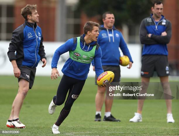 Andrew Swallow of the Kangaroos runs with the ball during a North Melbourne Kangaroos AFL training session at Arden Street Ground on August 4, 2017...