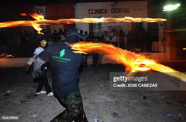 Participant in "La Recuerda" festival throws a fireball at his opponents in the main street of Nejapa, some 20 km north of San Salvador, on August...