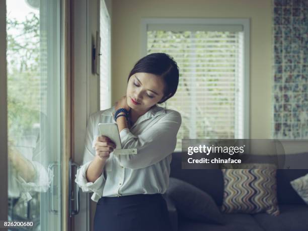 woman texting at window - person with a neck pain stock pictures, royalty-free photos & images