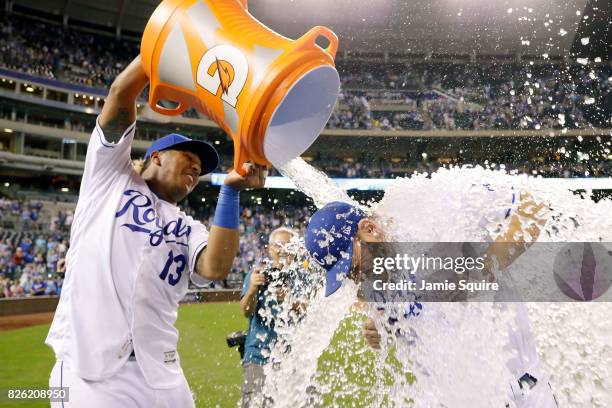 Brandon Moss of the Kansas City Royals is doused with water by catcher Salvador Perez as Kansas City Star photographer John Sleezer looks on after...