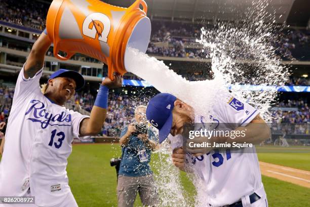 Brandon Moss of the Kansas City Royals is doused with water by catcher Salvador Perez as Kansas City Star photographer John Sleezer looks on after...