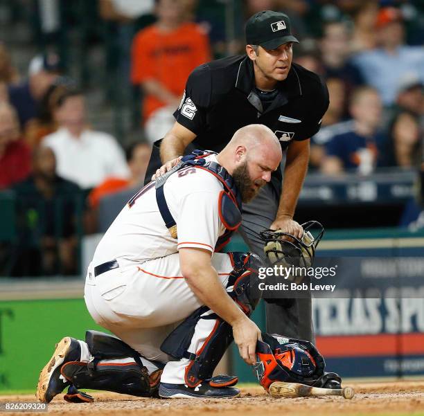 Evan Gattis of the Houston Astros takes a moment with home plate umpire James Hoye after he was hit in the head on the backswing of Corey Dickerson...