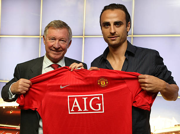 Dimitar Berbatov poses with Sir Alex Ferguson and a Manchester United shirt after signing for the club at Old Trafford on September 1, 2008 in...