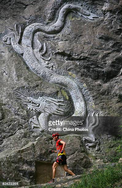 Contestant runs past a dragon engraved on the crag as he competes during the caving session of the Wulong Mountain Quest on September 1, 2008 in...
