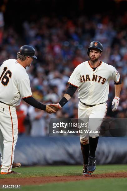 Brandon Belt of the San Francisco Giants is congratulated by third base coach Phil Nevin after hitting a two run home run against the Oakland...