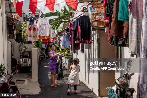 Woman hangs laundry in an alley in her neighborhood in Jakarta on August 4, 2017. / AFP PHOTO / Bay ISMOYO