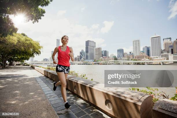 young woman jogging on brisbane southbank - brisbane people stock pictures, royalty-free photos & images
