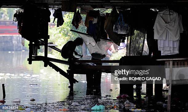 Filipino slum dweller with few belongings live under a bridge surrounded by a polluted river in Manila on September 1, 2008. Despite the Philippine...