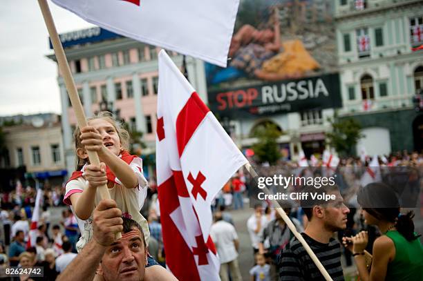 Georgians wave their national flag during a peace rally held in Republic Square, where a golden statue of Saint George, the patron saint of Georgia...