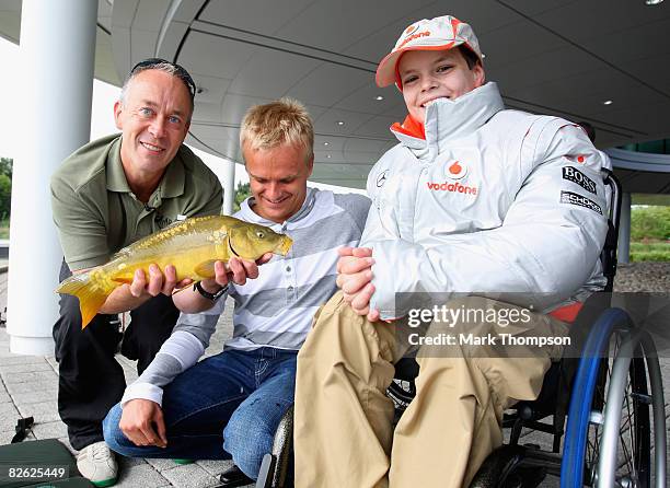 Britain's champion carp angler Martin Locke and McLaren Formula 1 driver Heikki Kovalainen of Finland pose with Liam Fairhurst, age 13, who has been...