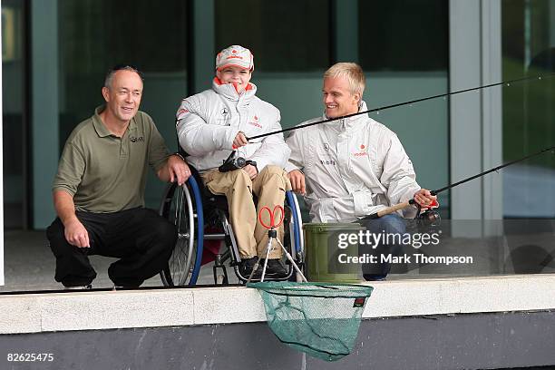 Britain's champion carp angler Martin Locke and McLaren Formula 1 driver Heikki Kovalainen of Finland fish with Liam Fairhurst, age 13, who has been...