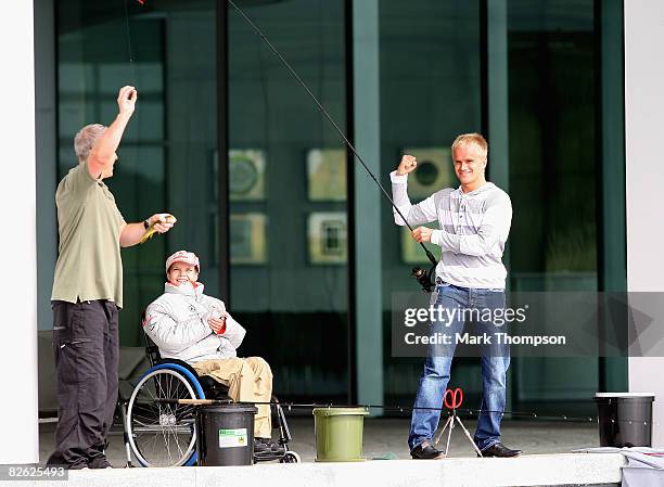 Britain's champion carp angler Martin Locke and McLaren Formula 1 driver Heikki Kovalainen of Finland fish with Liam Fairhurst, age 13, who has been...