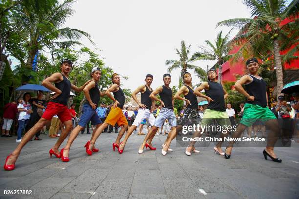 Men tourists wearing high-heeled shoes perform bamboo pole dancing during an activity on August 3, 2017 in Sanya, Hainan Province of China. A scenic...