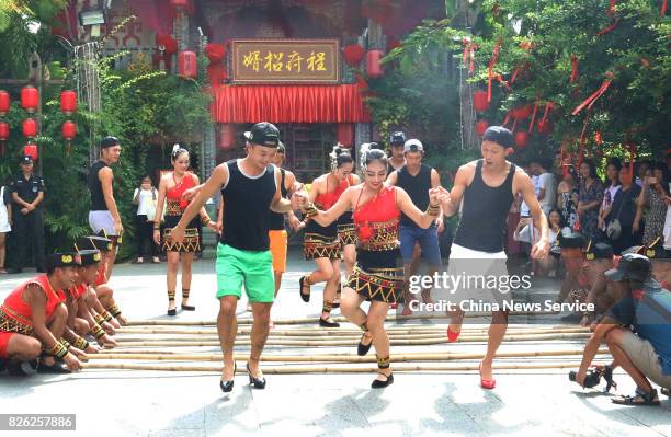 Men tourists wearing high-heeled shoes perform bamboo pole dancing during an activity on August 3, 2017 in Sanya, Hainan Province of China. A scenic...
