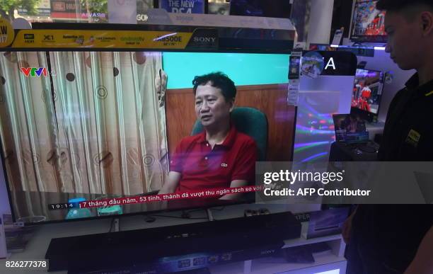 Store employee watches a screen showing Trinh Xuan Thanh speaking in a clip aired by Vietnam's state television VTV, in Hanoi on August 4, 2017....