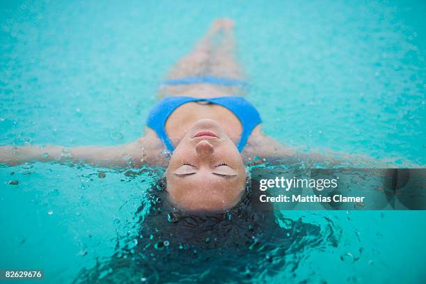 woman floats in lagoon while it rains - arm floats stock-fotos und bilder