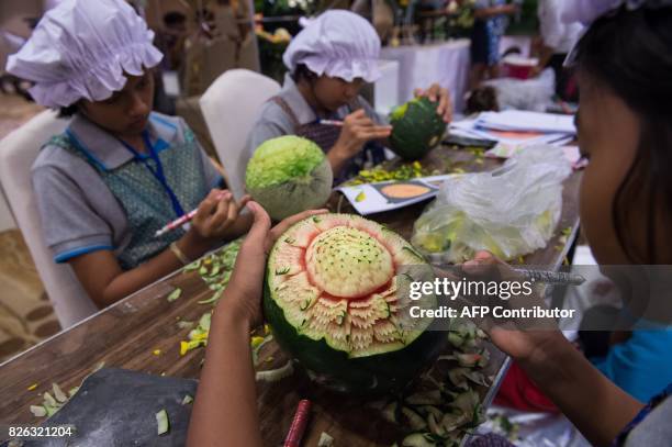 Thai girls carve floral patterns into fruits during a fruit and vegetable carving competition in Bangkok on August 4, 2017. It is a royal tradition...