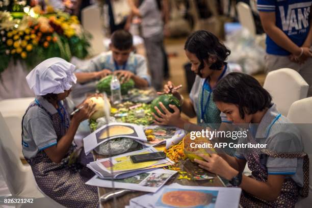 Thai children carve elaborate designs into fruit and vegetables during a fruit and vegetable carving competition in Bangkok on August 4, 2017. It is...