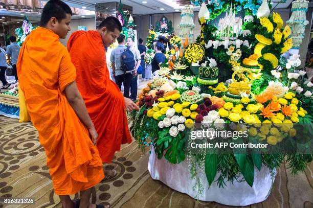 Two Buddhist monks look at an elaborate display of carved fruits and vegetables during a fruit and vegetable carving competition in Bangkok on August...