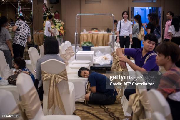 Girl sleeps on a chair as others put together elaborate fruit and vegetable displays during a fruit and vegetable carving competition in Bangkok on...