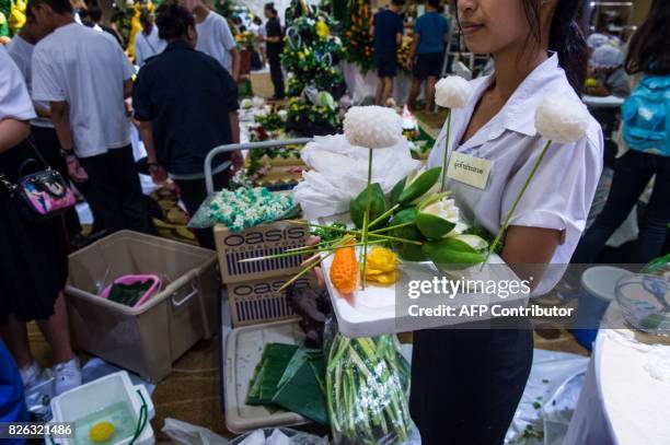 Thai woman holds a tray with carved fruit and vegetable decorations during a fruit and vegetable carving competition in Bangkok on August 4, 2017. It...