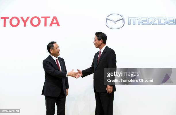 Toyota Motor Co. President Akio Toyoda, left, and Mazda Motor Co. President and CEO Masamichi Kogai, right, shake hands during a photo session at a...