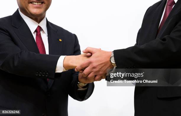 Toyota Motor Co. President Akio Toyoda, left, and Mazda Motor Co. President and CEO Masamichi Kogai, right, shake hands during a photo session at a...