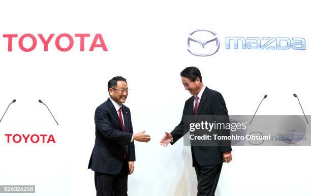 Toyota Motor Co. President Akio Toyoda, left, and Mazda Motor Co. President and CEO Masamichi Kogai, right, shake hands during a photo session at a...