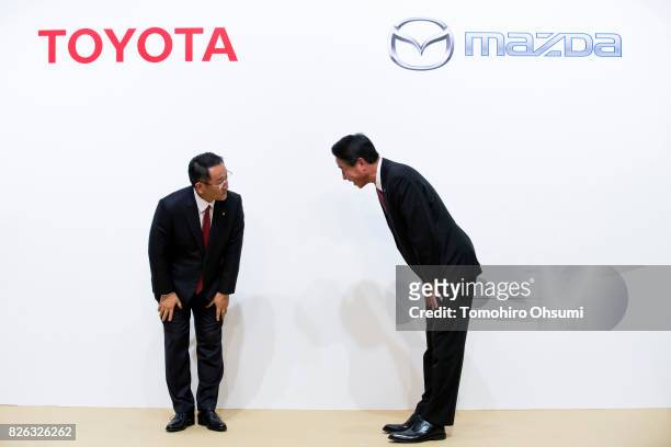 Toyota Motor Co. President Akio Toyoda, left, and Mazda Motor Co. President and CEO Masamichi Kogai, right, bow during a photo session at a joint...