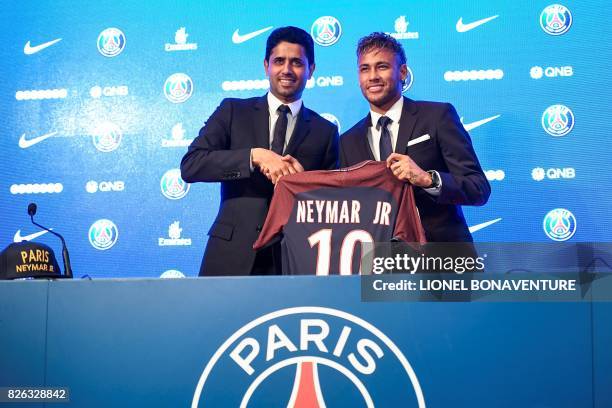 Brazilian superstar Neymar poses with his jersey next to Paris Saint Germain's Qatari president Nasser Al-Khelaifi during a press conference at the...