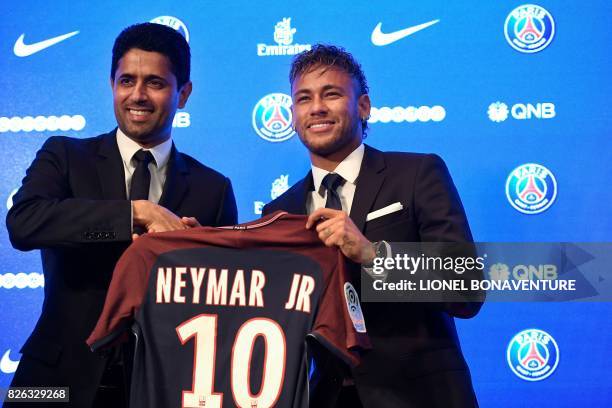 Brazilian superstar Neymar poses with his jersey next to Paris Saint Germain's Qatari president Nasser Al-Khelaifi during a press conference at the...