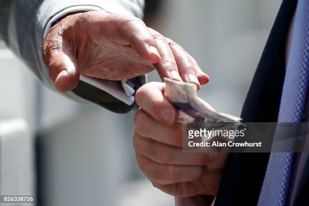 Bookmaker reaches for a punter's money on day four of the Qatar Goodwood Festival at Goodwood racecourse on August 4, 2017 in Chichester, England.