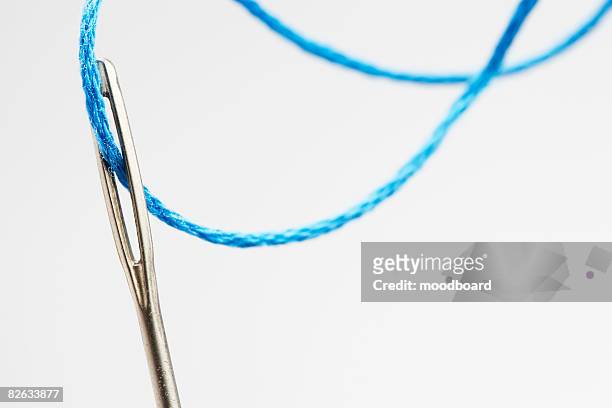 blue thread going through needle eye, close-up - sewing needle stock pictures, royalty-free photos & images