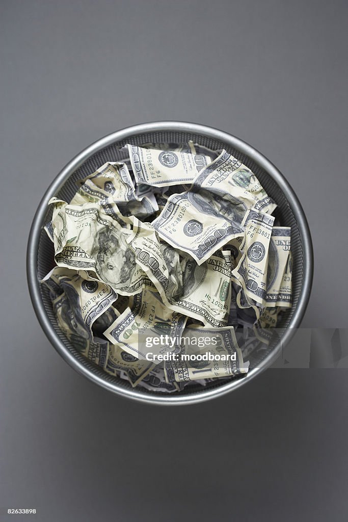 Dollar bills in wastebasket, view from above