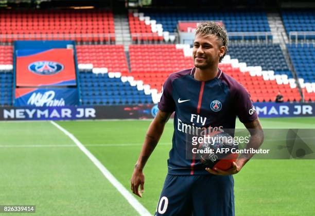 Brazilian superstar Neymar poses with a ball during his official presentation at the Parc des Princes stadium on August 4, 2017 in Paris after...