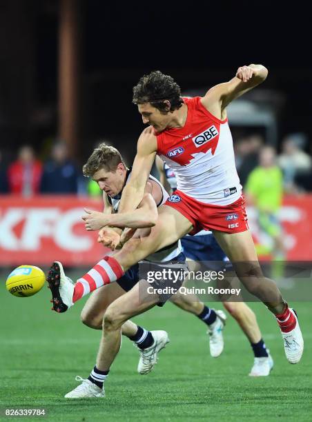 Kurt Tippett of the Swans kicks whilst being tackled by Scott Selwood of the Cats during the round 22 AFL match between the Geelong Cats and the...