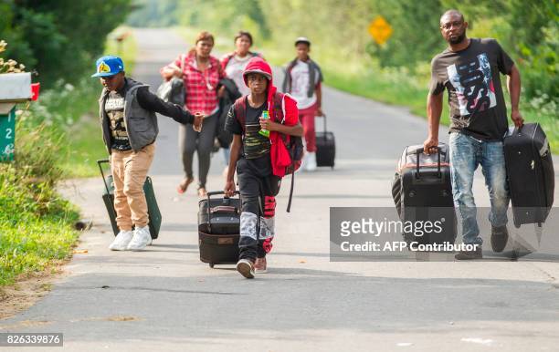 Group of people who claimed to be from Haiti walk down Roxham road in Champlain, New York as they prepare to cross the border into Canada illegally...